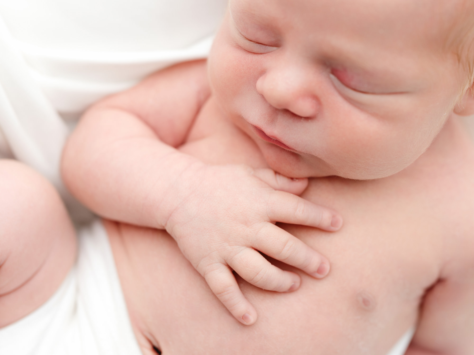 Newborn baby resting peacefully in arms.