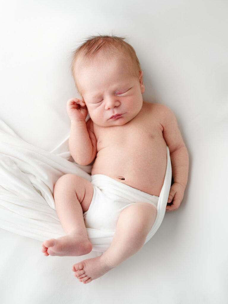Newborn baby wrapped in white fabric.