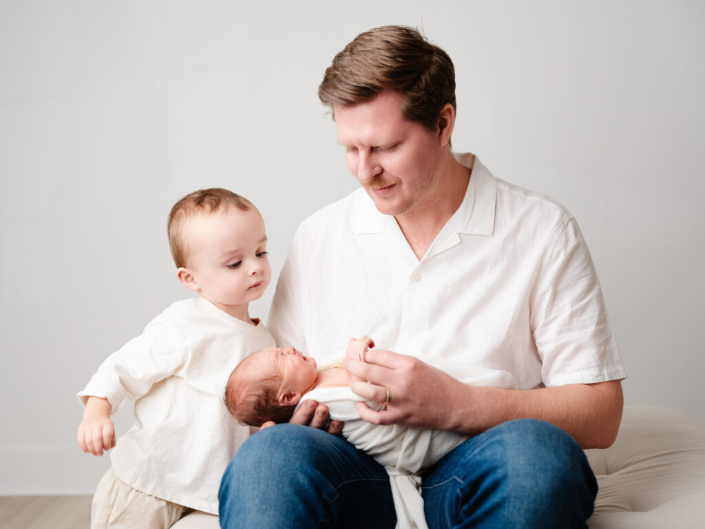 Big brother looking at newborn sibling during family newborn session