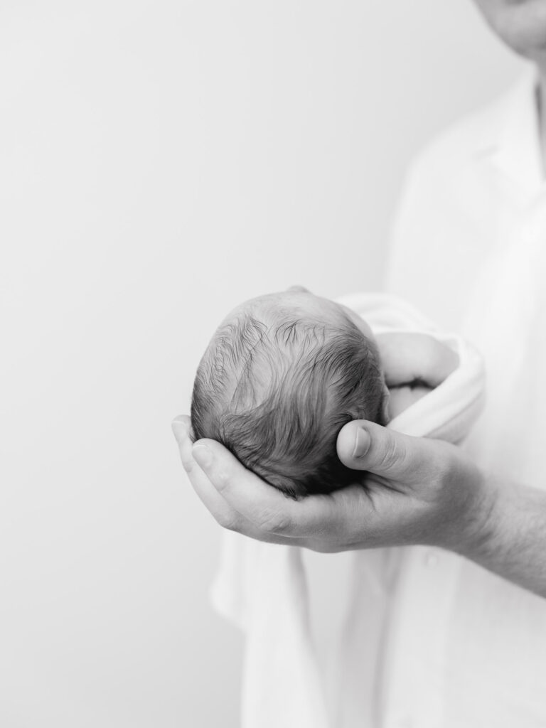 Father holding newborn son during lifestyle studio session in Roseville