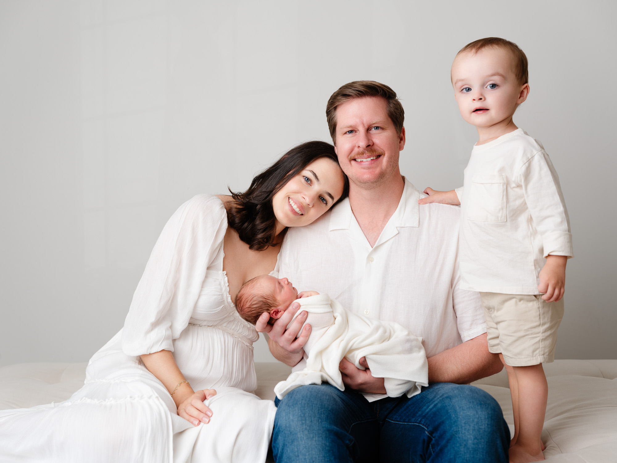Natural newborn photography in a Roseville studio with parents and big brother holding their baby boy