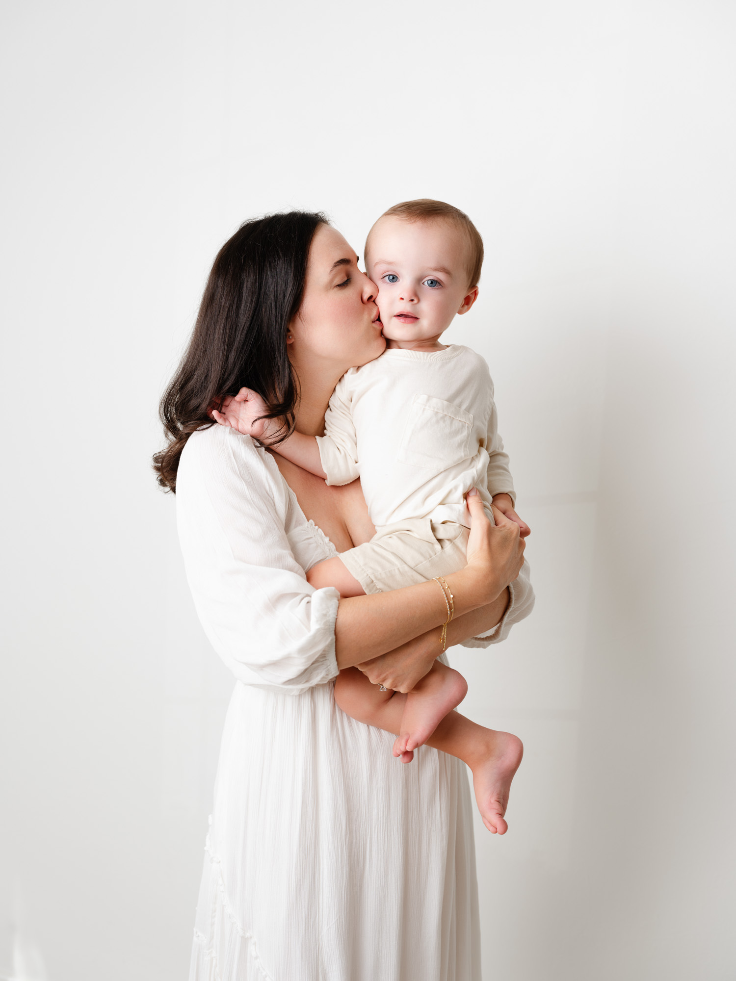 Big brother being snuggled by mama during newborn session in studio