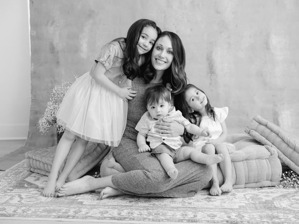 Mother holding her three children on a fine art backdrop