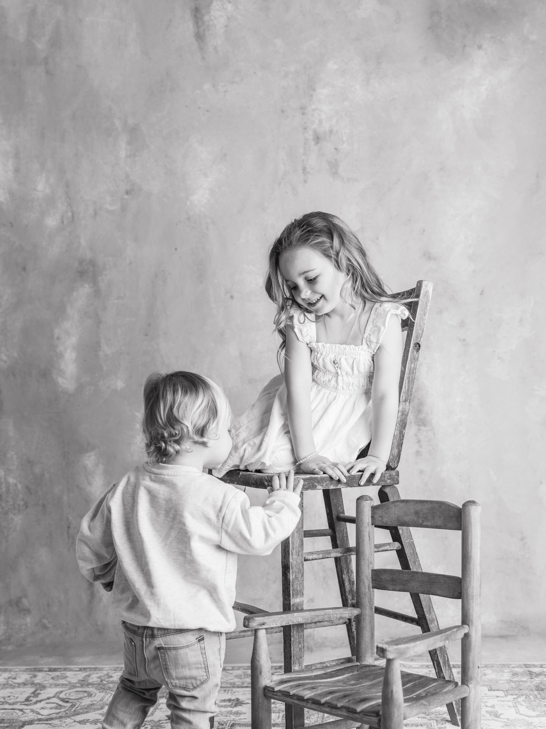 Timeless black and white childhood portrait of siblings sharing a gentle moment in a studio setting.