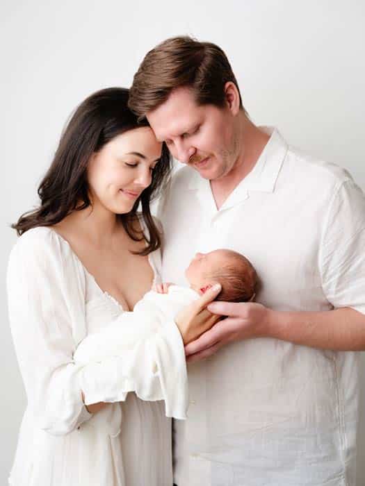 Parents holding newborn baby in neutral studio setting